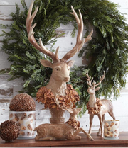 Decorative deer figurines with antlers and floral details against a green wreath.