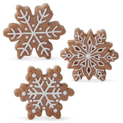 A set of three gingerbread snowflake-shaped figurines with white icing details on a white background.