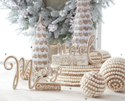 Decorative Christmas items including wooden trees, beads, and 'Merry Christmas' sign in a festive setting.
