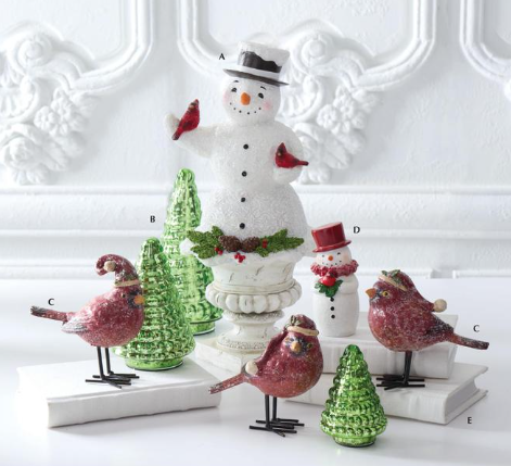 Decorative snowman and birds figurines on a white surface with a decorative wall background.
