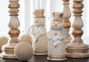 Decorative snowmen with wooden candle holders and spherical ornaments on a white background