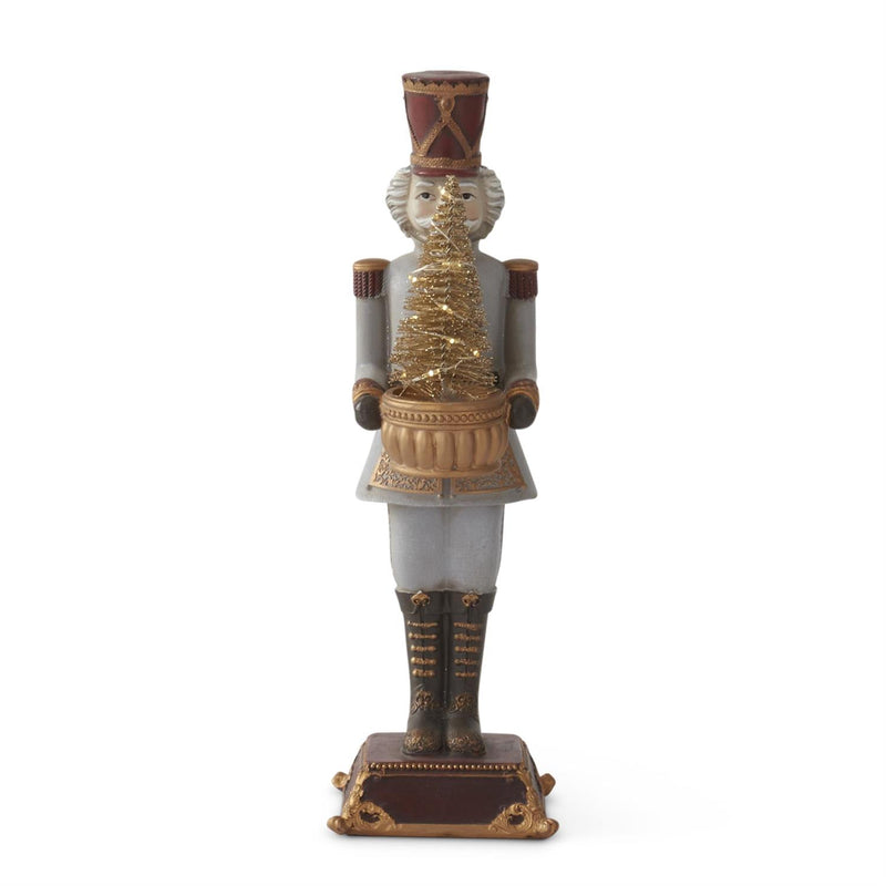 A decorative nutcracker figurine with a gold LED tree on its chest, wearing a traditional soldiery uniform with a red hat.