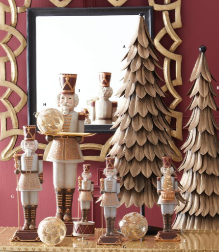Decorative Christmas trees and nutcrackers on a table with a mirror and decorative wall.
