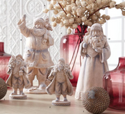 Decorative Santa Claus figurines with red vases and beige branches on a light background