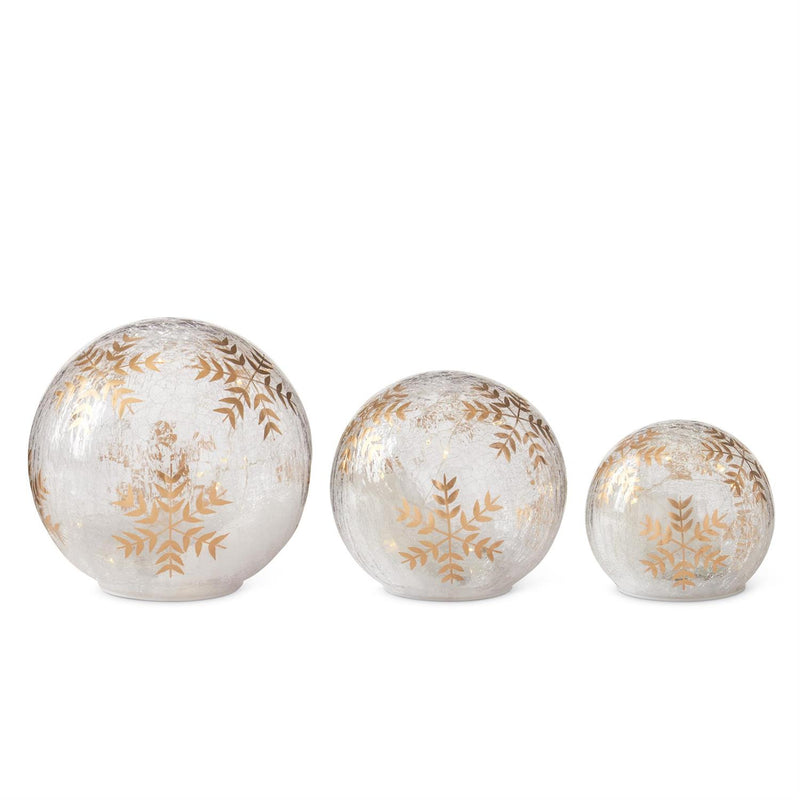 Three decorative spherical ornaments with gold leaf patterns on a white background