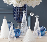 Decorative Christmas trees with white candles and blue ornaments on a table.