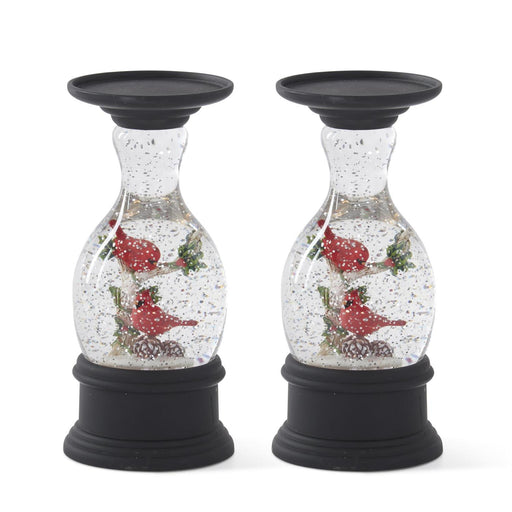 Two decorative candle holders with snow globe effect and cardinal birds on a white background