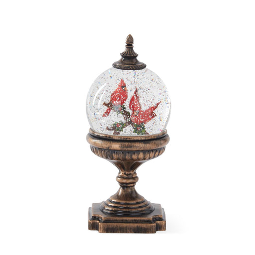 Decorative snow globe with red cardinals on a wooden base against a white background
