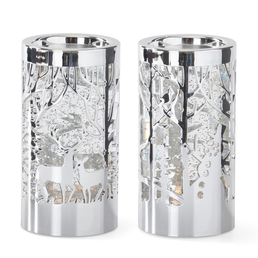 Two silver candle holders with deer and tree cutouts on a white background