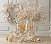 Decorative arrangement with dried plants, a vase, and spherical objects on a neutral background