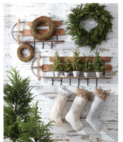 Decorative wall with wreaths, plants, and stockings on a rustic wooden background