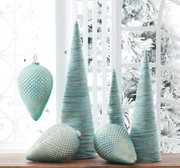 Set of teal textured Christmas ornaments on a wooden surface with a white lattice background.