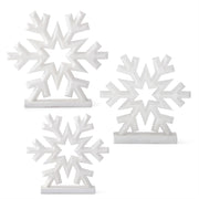 A set of three white glittered snowflake decorations on a base, in different sizes.