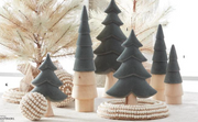 Decorative Christmas trees made of wood and felt on a white surface with a blurred background.