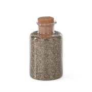 A cylindrical glass jar with gold glitter sand, topped with a cork stopper.