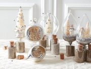 Decorative items including small trees, bottles, and jars on a white surface with a white background.