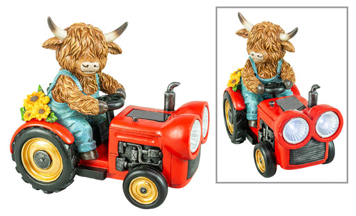 A decorative figurine of a shaggy brown cow driving a red tractor, shown from two angles on a white background. The cow is wearing blue overalls and there are yellow flowers on the side of the tractor.