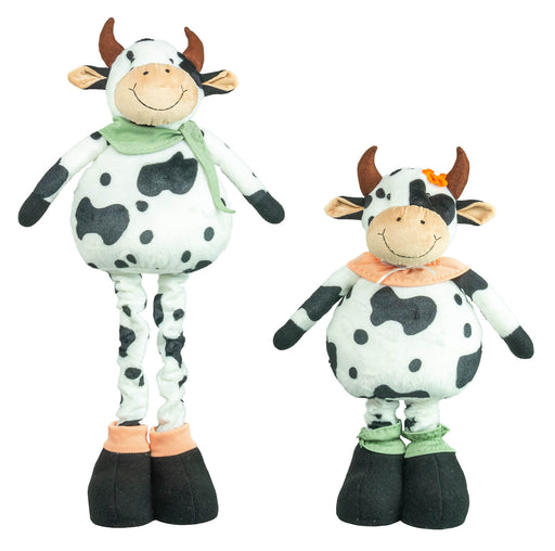 Two cow-shaped plush toys on a plain white background, one tall and one short, both with black-and-white spotted bodies, brown horns, smiling faces, and different colored neck scarves and hooves.