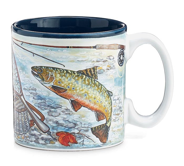 A white ceramic mug featuring a detailed illustration of a brown trout jumping in a rocky stream, with a fishing rod, fly, and a dark blue interior rim.