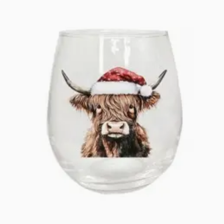 A clear stemless wine glass featuring a printed illustration of a brown highland cow wearing a red Santa hat, set against a plain white background.