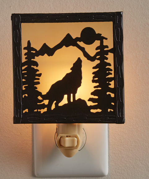 Night light with a wolf and mountain design on a beige wall.