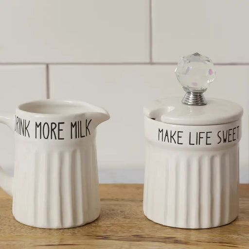 Two ceramic containers with text on a wooden surface and tiled wall background