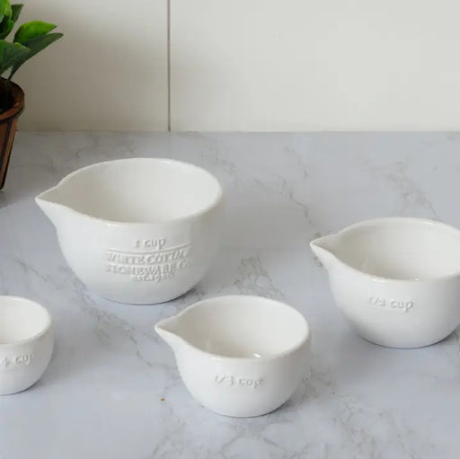 Set of white ceramic measuring cups on a marble countertop
