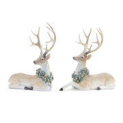 Two deer figurines with antlers and floral wreaths on a white background