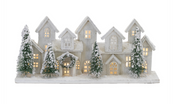 Decorative model of a snowy village with lit windows on a white background