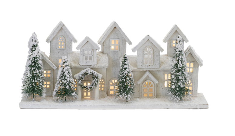 Decorative model of a snowy village with lit windows on a white background
