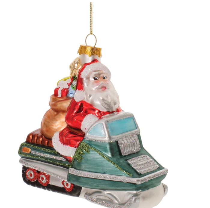 Glass ornament of Santa Claus driving a green car with a white roof on a white background