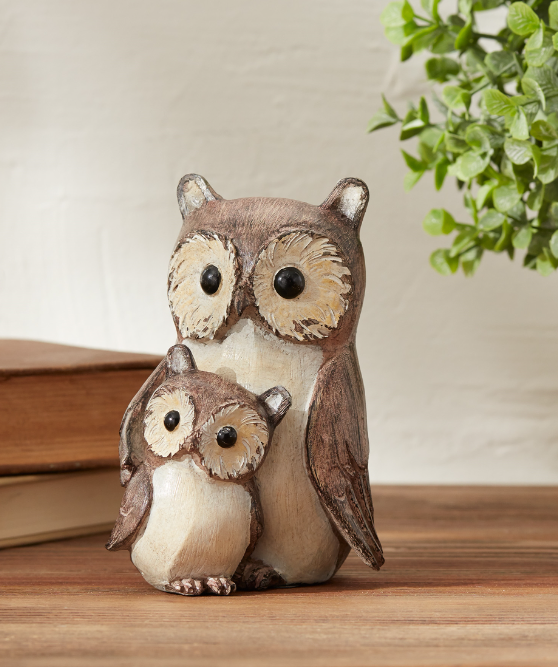 Wooden owl figurine on a wooden surface with a plant in the background