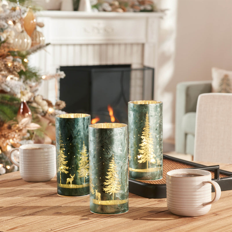 Decorative candles with forest design on a table in a cozy living room.
