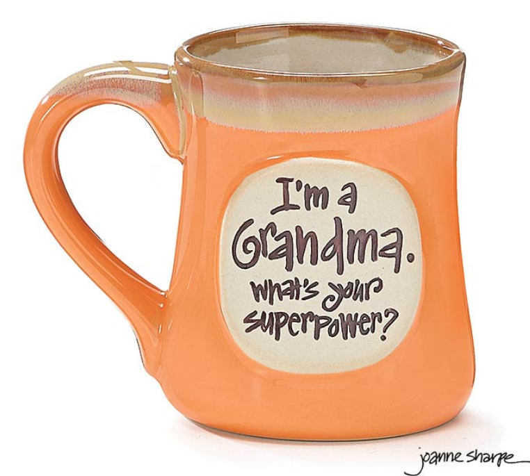 A hand-painted porcelain peachy orange mug with a taupe rim and top of handle, featuring a raised cream message area on the front that reads 'I'm a GRANDMA. What's Your Superpower?'.
