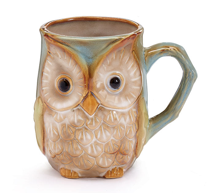 A ceramic mug with a blue green base and an owl design with details on the face and wings.