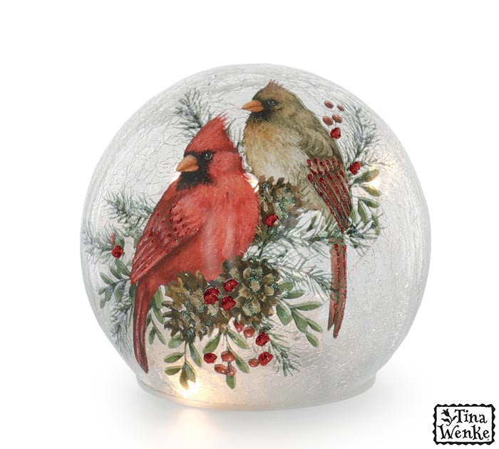 Decorative glass ball with cardinals and winter elements on a white background