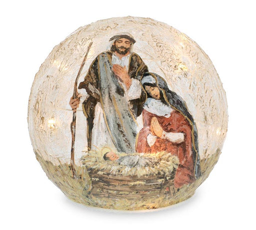 A decorative spherical Christmas ornament featuring a painted nativity scene with Mary, Joseph, and baby Jesus in a manger, illuminated from within on a white background.