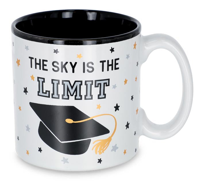 A white ceramic mug with a black interior and rim, featuring the printed text 'THE SKY IS THE LIMIT' above a black graduation cap with a gold tassel, surrounded by small scattered stars in black, gray, and gold.