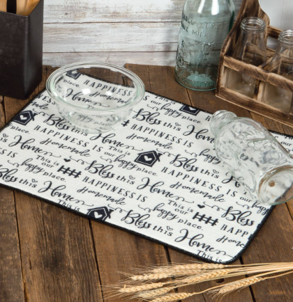 Decorative tray with text on a wooden surface with jars and a bottle in the background.