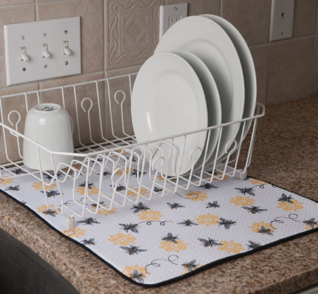 Dish rack with plates on a kitchen counter featuring a decorative mat.