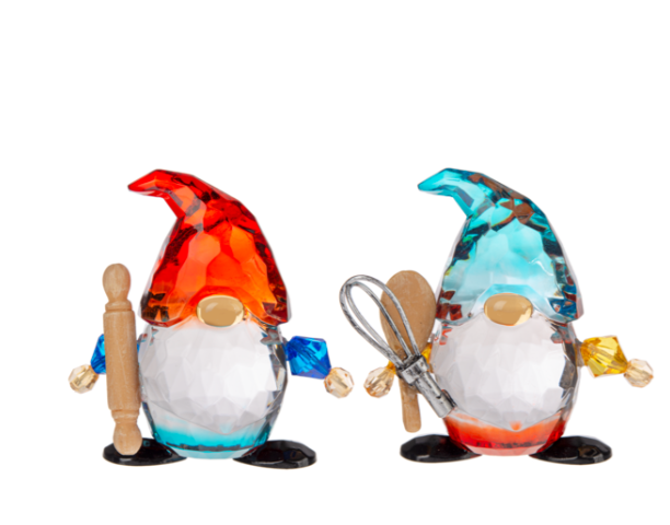 Two glass gnome figurines with colorful hats and kitchen utensils on a white background