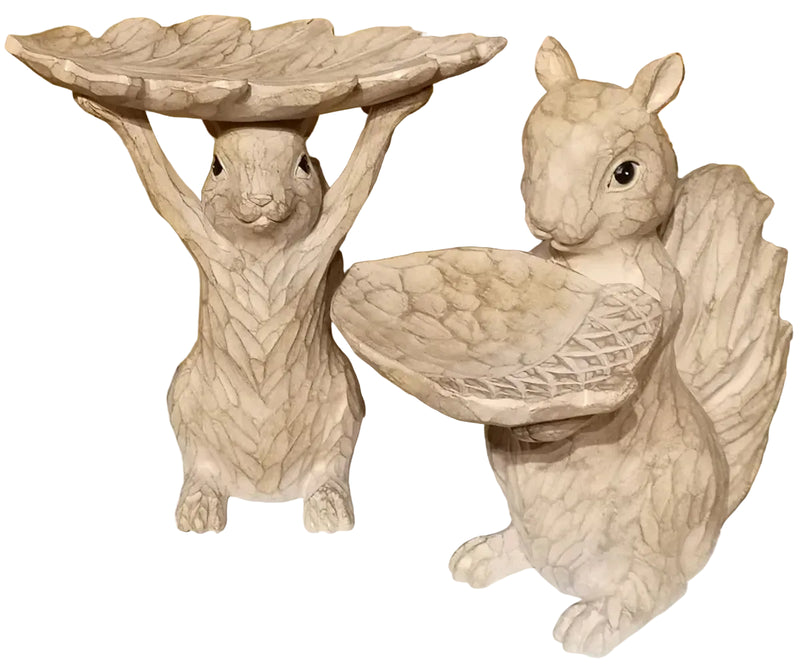 Two squirrel statues with bird baths on a decorative surface.