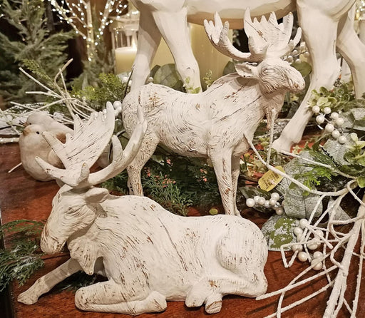 Decorative white moose figurines on a wooden surface.