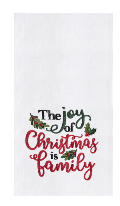 A white kitchen towel with red and green text that reads 'The Joy of Christmas Family' and is adorned with holly berry icons.