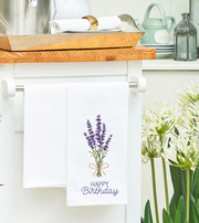 Kitchen towel with lavender design and 'Happy Birthday' text hanging on a kitchen cabinet.