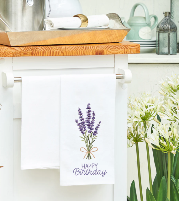 Kitchen towel with lavender design and 'Happy Birthday' text hanging on a kitchen cabinet.