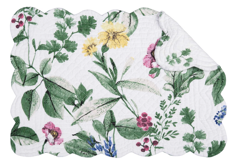 A white quilted placemat with floral print in green, pink, yellow