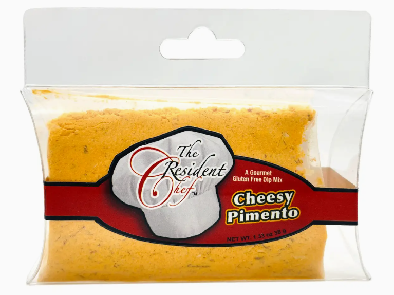 Packaged Cheesy Pimento dip in a clear plastic pouch with red and white branding for The Resident Chef brand.