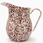 Speckled enamel pitcher with red and white pattern on a white background