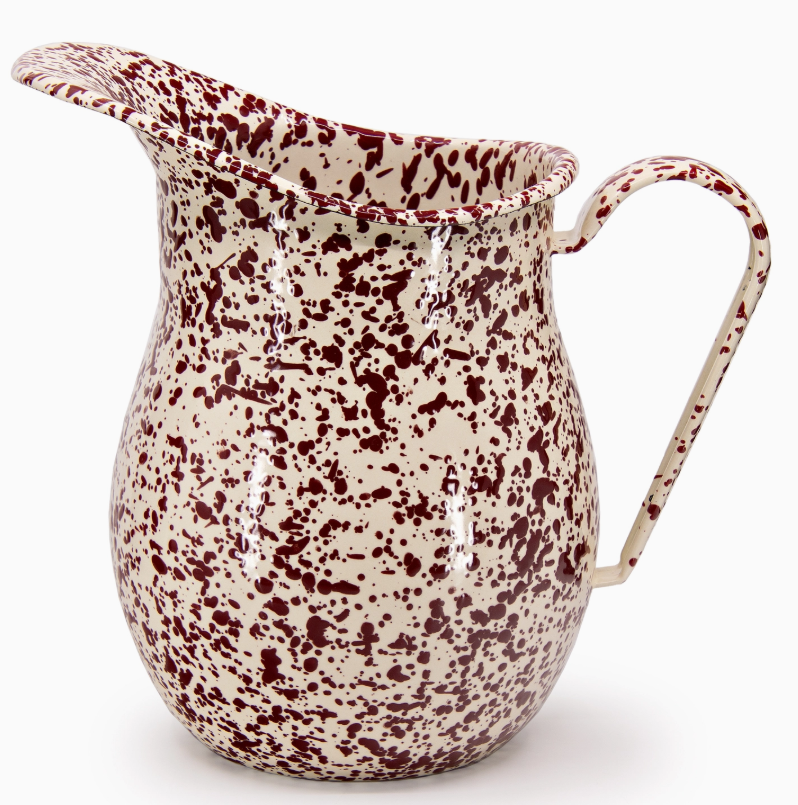 Speckled enamel pitcher with red and white pattern on a white background